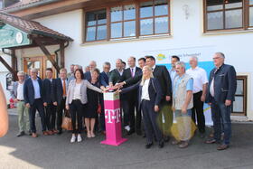 Teilnehmerinnen und Teilnehmer der Breitbandausbauabschlussveranstaltung in Neunburg vorm Wald mit Staatsminister Albert Füracker (Mitte) stehen vor einem Turm 