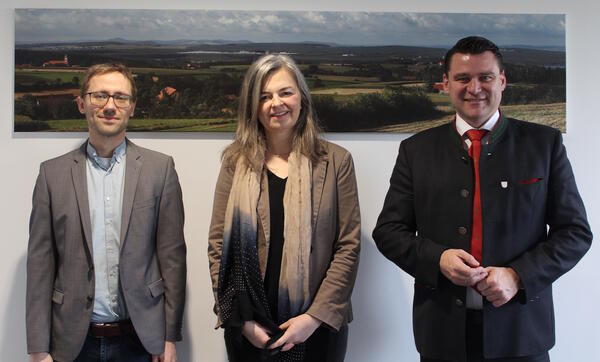 Die neue MINT-Managerin steht neben zwei M&auml;nnern vor einem Bild vom Landkreis Schwandorf