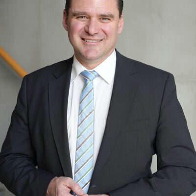 Der Landrat steht vor einer grauen Wand