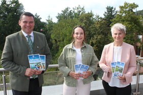 Ein Mann und zwei Frauen halten jeweils zwei neue Brosch&uuml;ren in den H&auml;nden.
