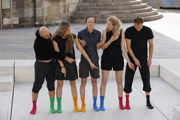 Frauen und M&auml;nner in schwarzer Kleidung und mit bunten Socken stehen nebeneinander
