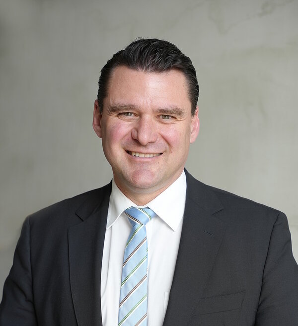 Der Landrat steht vor einer grauen Wand