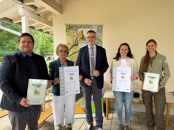 Zwei Frauen und zwei M&auml;nner stehen auf der Terrasse vom Kindergarten. Sie halten Urkunden in den H&auml;nden.