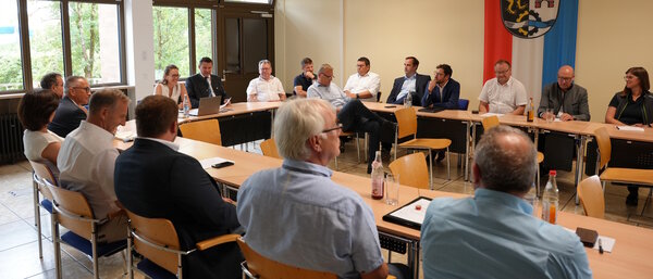 Frauen und M&auml;nner sitzen in einem Saal. Im Hintergrund sieht man die Fahne vom Land-Kreis Schwandorf