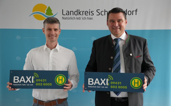 Zwei M&auml;nner halten Schilder in den H&auml;nden. Die Schilder werden sp&auml;ter an Stellen angebracht, wo das BAXI anhalten darf.