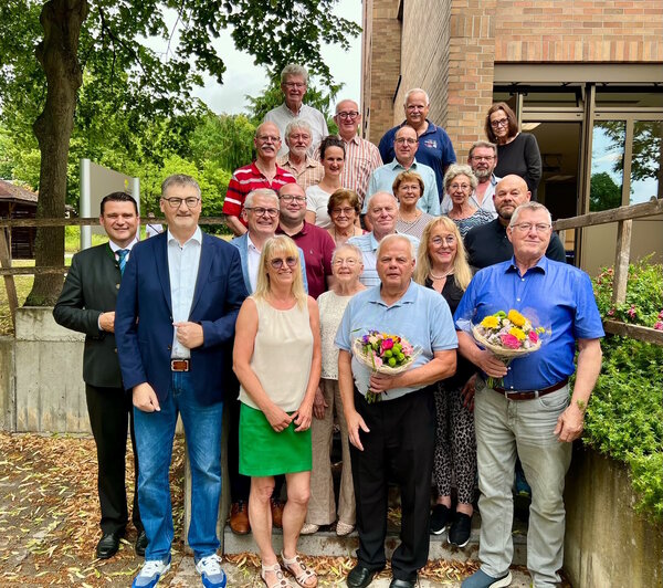 Mehrere Frauen und M&auml;nner stehen auf der Terrasse vom Landratsamt. Zwei M&auml;nner halten einen Blumenstrau&szlig; in der Hand.