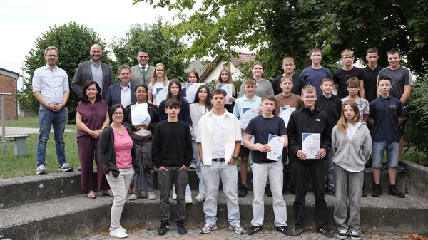 Sch&uuml;ler und Erwachsene stehen auf einer 