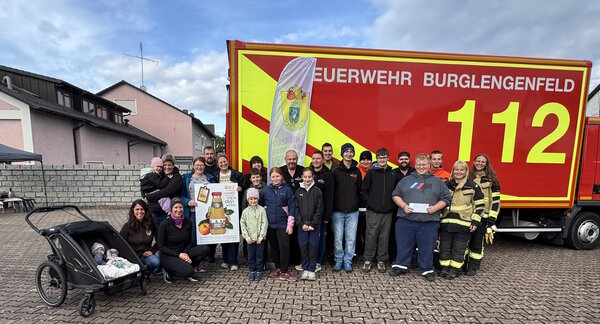 Erwachsene und Jugendliche stehen vor einem Feuerwehrauto